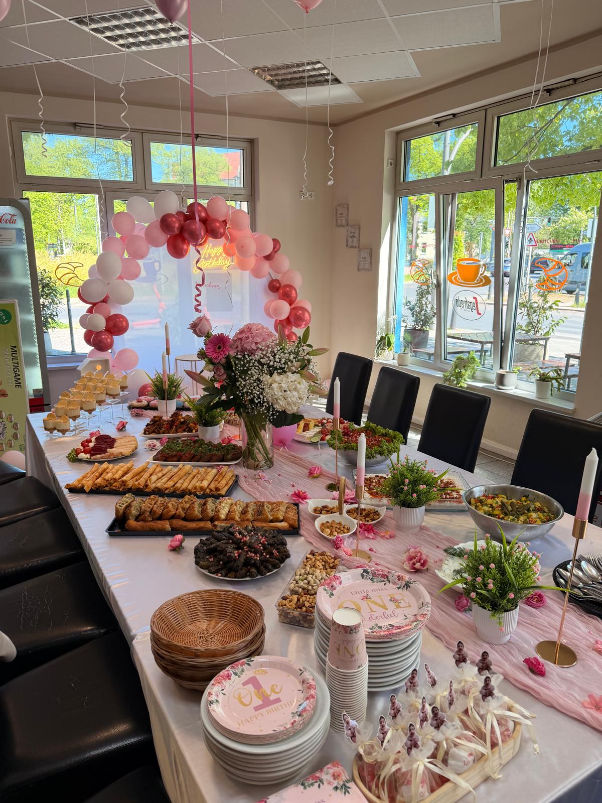 Rosa dekoriertes Buffet mit Blumen, orientalischen Spezialitäten und Deko zum ersten Geburtstag